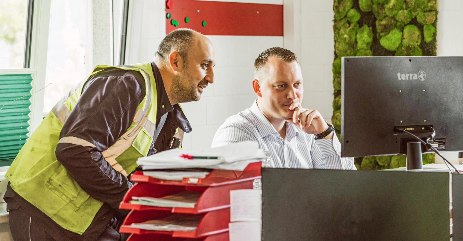 Zwei Mitarbeiter schauen auf einen Bildschirm